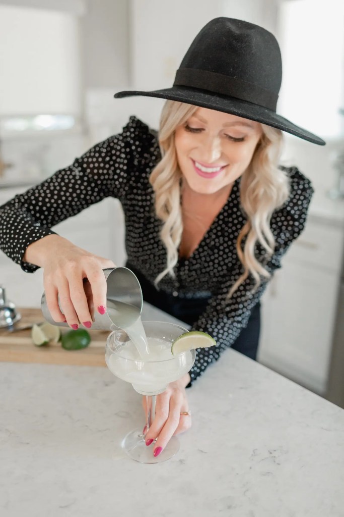 Woman pouring drink with lime garnish