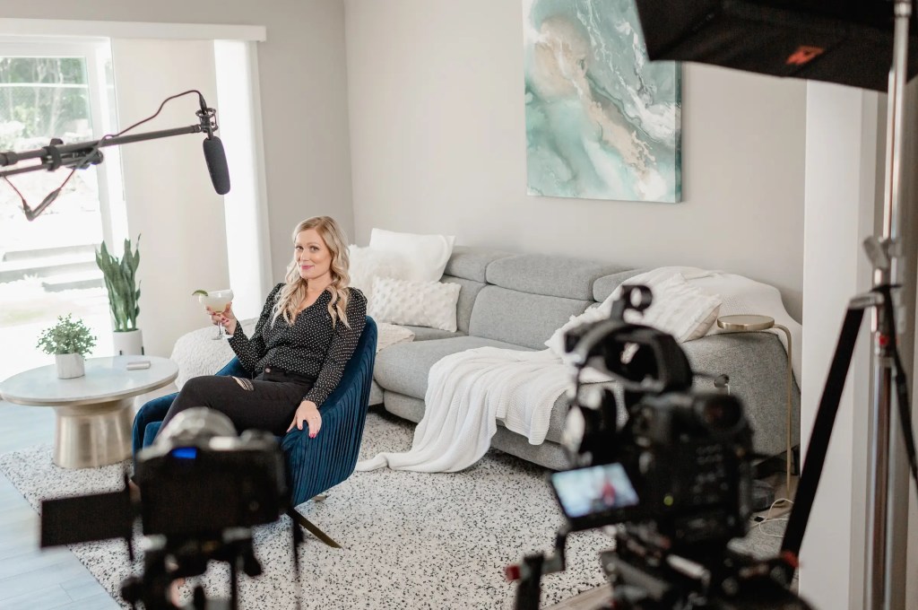 Woman sitting with drink in studio setup for a marketing video during brand photography pictures